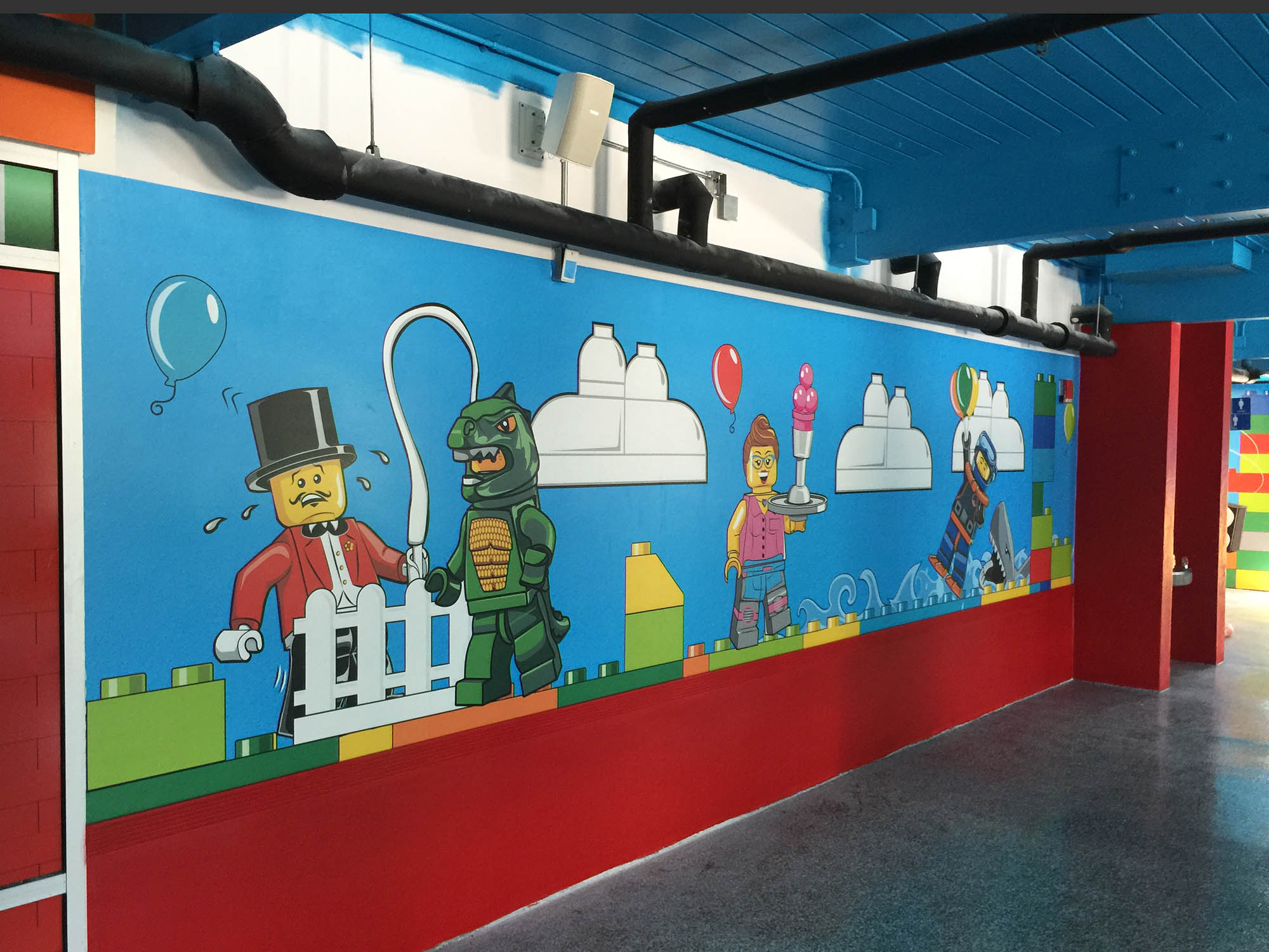 Graphic wall wrap for LEGOLAND Florida featuring minifigs among balloons and lego clouds.