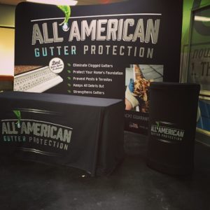 All American Trade Show Setup Trade show display setup with black table throw, podium cover, and backwall